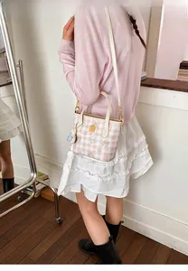 Detail shot of a pink plaid handbag featuring cute bear patterns and plush bear charm