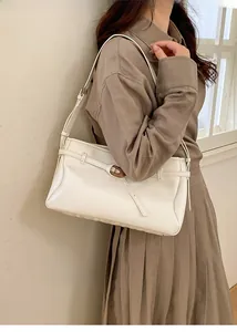 Side view of white glossy rectangular underarm bag with gold buckle on model