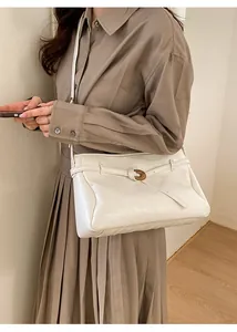 Detailed view of white pleated leather crossbody bag with oval metal buckle on a model