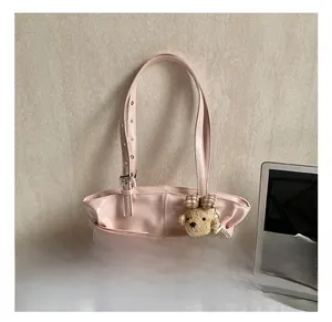 Detail of pink pleated armpit bag with adjustable buckle and cute bear charm decoration