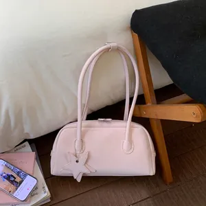 Top view of a minimalist pale pink bowling handbag with star charm on a bed surface