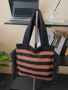 Sac cabas en maille rayée orange et noir avec franges latérales dans un cadre lifestyle