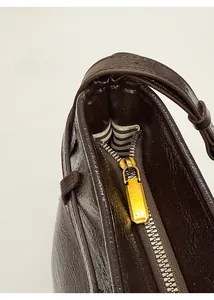 Detail of gold metal zipper and striped fabric lining on dark brown leather bag