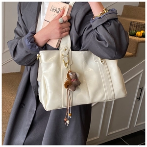Dettaglio di una borsa tote bianco crema con un simpatico portachiavi a scoiattolo