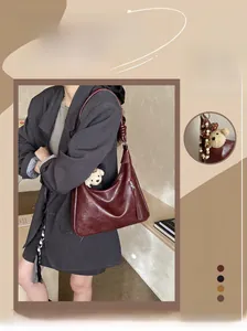 Détail du sac demi-lune bordeaux avec décor zip et breloque ours en peluche