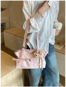 Close-up of pink glossy underarm bag featuring a metal buckle and brown teddy bear charm