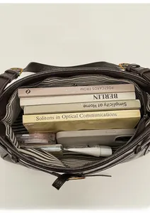 Top-down view of large brown leather tote interior with striped lining and daily items