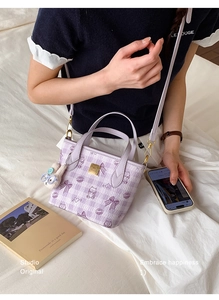 Detail of purple checkered tote bag with cartoon prints and plush rabbit pendant