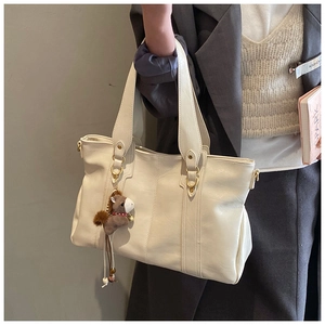 Dettaglio borsa tote in pelle beige con manico ad anello oro e ciondolo a cavallo