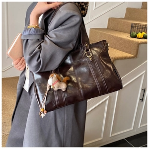 Dettaglio della borsa tote marrone scuro in pelle oleosa con ciondolo a forma di cavallo