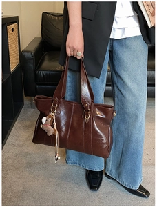 Dettaglio della borsa tote in pelle PU marrone scuro lucida con un simpatico ciondolo