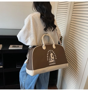 Dettaglio della grande borsa da viaggio che mostra il patchwork marrone e beige e la nave