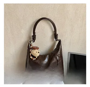 Détail du sac cabas en cuir huilé marron foncé avec un joli pendentif ours en peluche