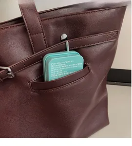 Détail de la poche avant du fourre-tout en cuir bordeaux montrant le rangement