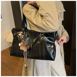 Dettaglio borsa shopper nera lucida con cuciture in pelle e ciondolo a cavallo