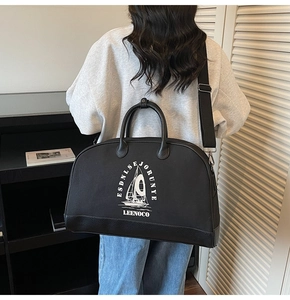 Dettaglio di una grande borsa da viaggio nera con grafica stampata e tracolla regolabile