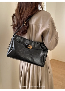Detail of minimalist retro tote bag showing polished texture and gold buckle on shoulder