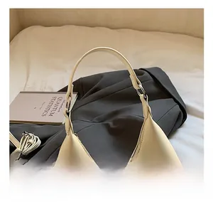 Vue détaillée du sac demi-lune crème en PU avec bandoulière sur une veste grise