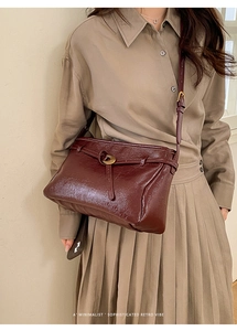 Detail of burgundy retro tote bag with gold buckle on a model in minimalist outfit