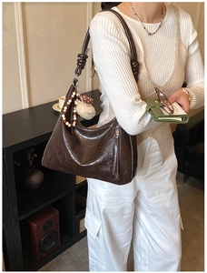 Détail du sac hobo marron avec bandoulière nouée et texture en cuir ciré vintage