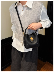 Modische schwarze Bucket Bag aus Leder mit goldener Schließe getragen am Modell