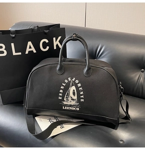 Dettaglio borsa da viaggio in tela nera con manici in pelle e stampa del logo bianco