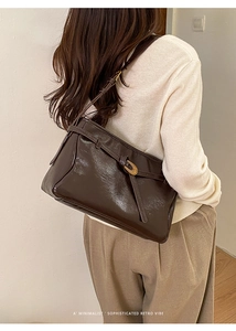 Detail of vintage dark brown faux leather shoulder bag with golden oval buckle hardware
