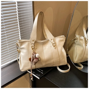 Dettaglio della borsa tote in finta pelle bianco sporco con ciondolo a forma di pony