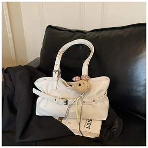 Close-up of white glossy tote bag with belt buckle detail and brown teddy bear charm