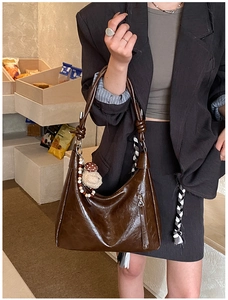Détail macro d'un sac hobo marron foncé avec bandoulière nouée et pendentif champignon