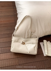Detail of vintage cream shoulder bag with bronze buckle and soft leather texture