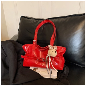 Close-up of a high-gloss red patent leather tote bag featuring a cute plush puppy charm