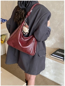 Détail d'un sac cabas bordeaux avec fermetures éclair argentées et un charm en peluche doux