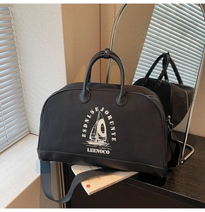 Dettaglio della borsa da viaggio nera con stampa di barca a vela e finiture in pelle