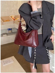 Gros plan du sac cabas rouge foncé vintage avec texture cirée et breloque ours