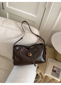 Detail of dark brown glossy leather tote with elegant golden circular metal buckle