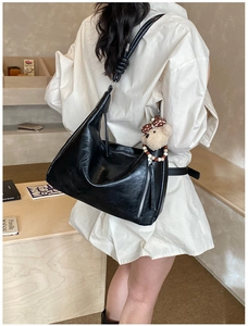 Détail d'un sac hobo noir effet brillant avec pendentif ours en peluche sur mannequin