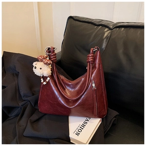 Détail du sac cabas en cuir marron foncé avec poignées nouées et breloque ours
