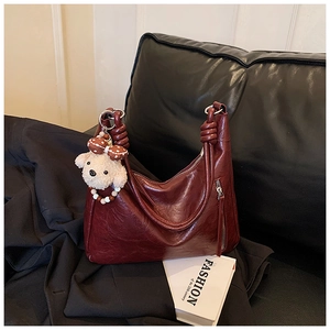 Vue détaillée du sac hobo bordeaux avec poignée nouée et breloque ours en peluche