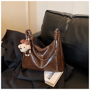 Détail du sac cabas marron vintage montrant le cuir ciré et le pendentif ours mignon