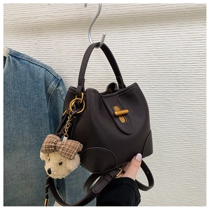 Detail der dunkelbraunen Beuteltasche aus genarbtem Leder mit Drehverschluss und Bärenanhänger