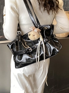 Glossy black wrinkled tote bag with silver buckle and bear charm shown on model
