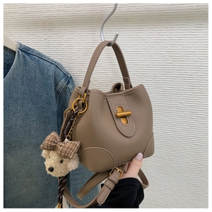 Detail der taupefarbenen Beuteltasche aus Leder mit goldenen Beschlägen und Anhänger