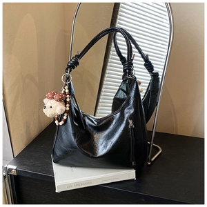 Détail du sac hobo noir en demi-lune avec nœuds latéraux et pendentif ours en peluche