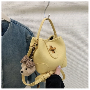 Detail der gelben Beuteltasche aus Leder mit goldenem Verschluss und Bärenanhänger