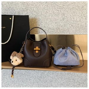 Detailansicht der dunkelbraunen Leder-Eimertasche mit Goldschloss und Bärenanhänger