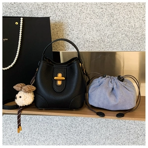 Detail der schwarzen Beuteltasche aus genarbtem Leder mit goldenem Verschluss und Anhänger
