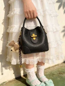 Klassische schwarze Eimertasche aus Leder mit Metallschloss und Teddybär-Anhänger