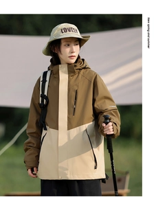 Close-up of hooded outdoor jacket with contrast panels and trekking pole detail