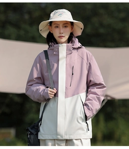 Outdoor detail of a pink and white waterproof windbreaker featuring zip pockets and hood